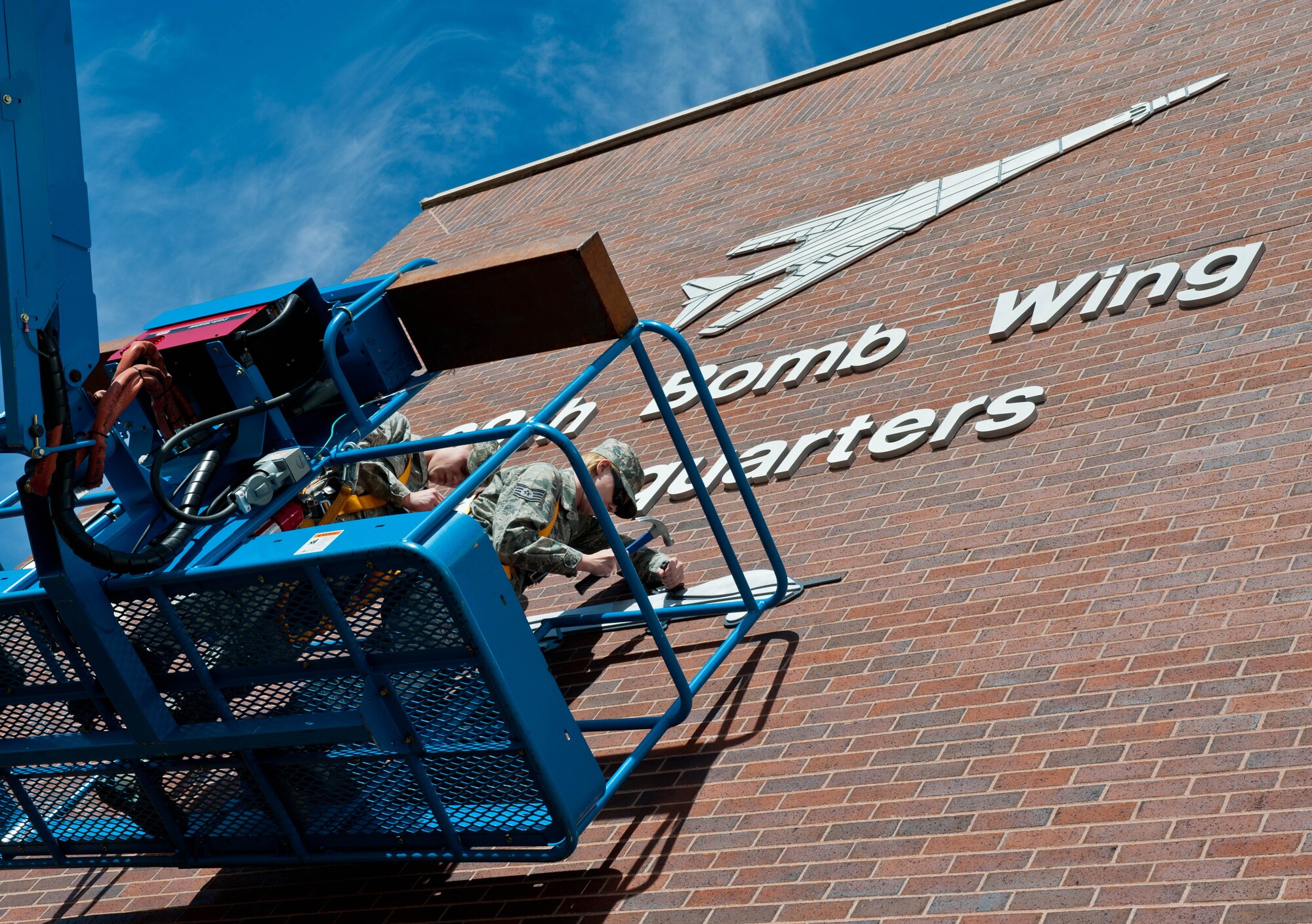 Senior Airman Michael Maze, and Staff Sgt. Amanda Fischer, 28th Civil Engineer Squadron structural technicians, affix a MQ-9 Reaper image to the front of the 28th Bomb Wing Headquarters building at Ellsworth Air Force Base, S.D., Oct. 29, 2012. The 432nd ATKS controls unmanned MQ-9 Reaper aircraft during missions over Southwest Asia from ground control facilities at Ellsworth, in support of national security objectives. (U.S. Air Force photo by Airman 1st Class Zachary Hada/Released)