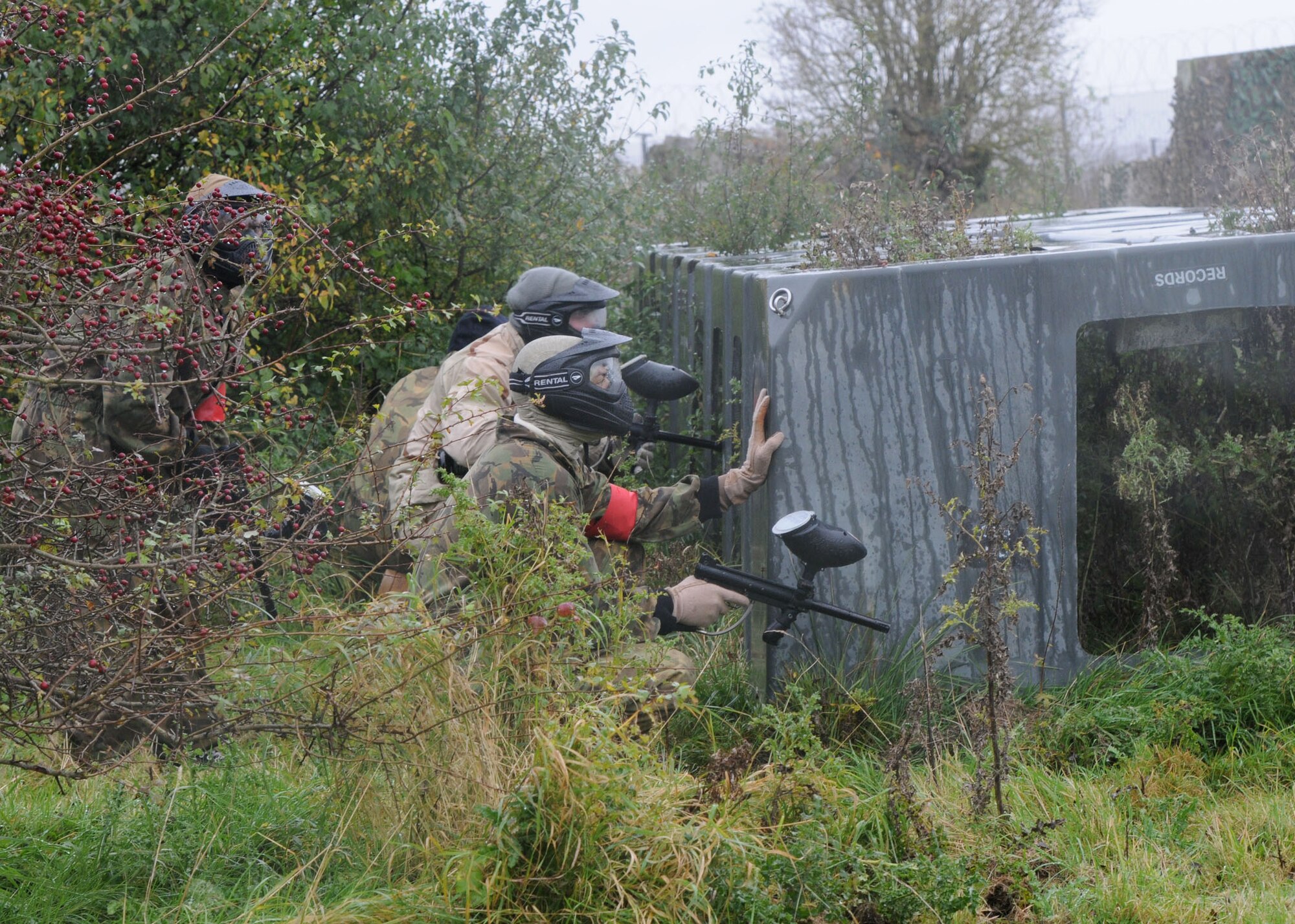 Service members on the RAF Alconbury and RAF Molesworth team wait behind barriers to shoot at members of the opposing team at the Single Airman Retreat Paintball Tournament Nov. 3, 2012, on RAF Molesworth, England. Players were tagged out of each 10 minute game if they were shot and the paint ball broke on their coveralls. (U.S. Air Force photo by Airman 1st Class Kelsey Waters/Released)