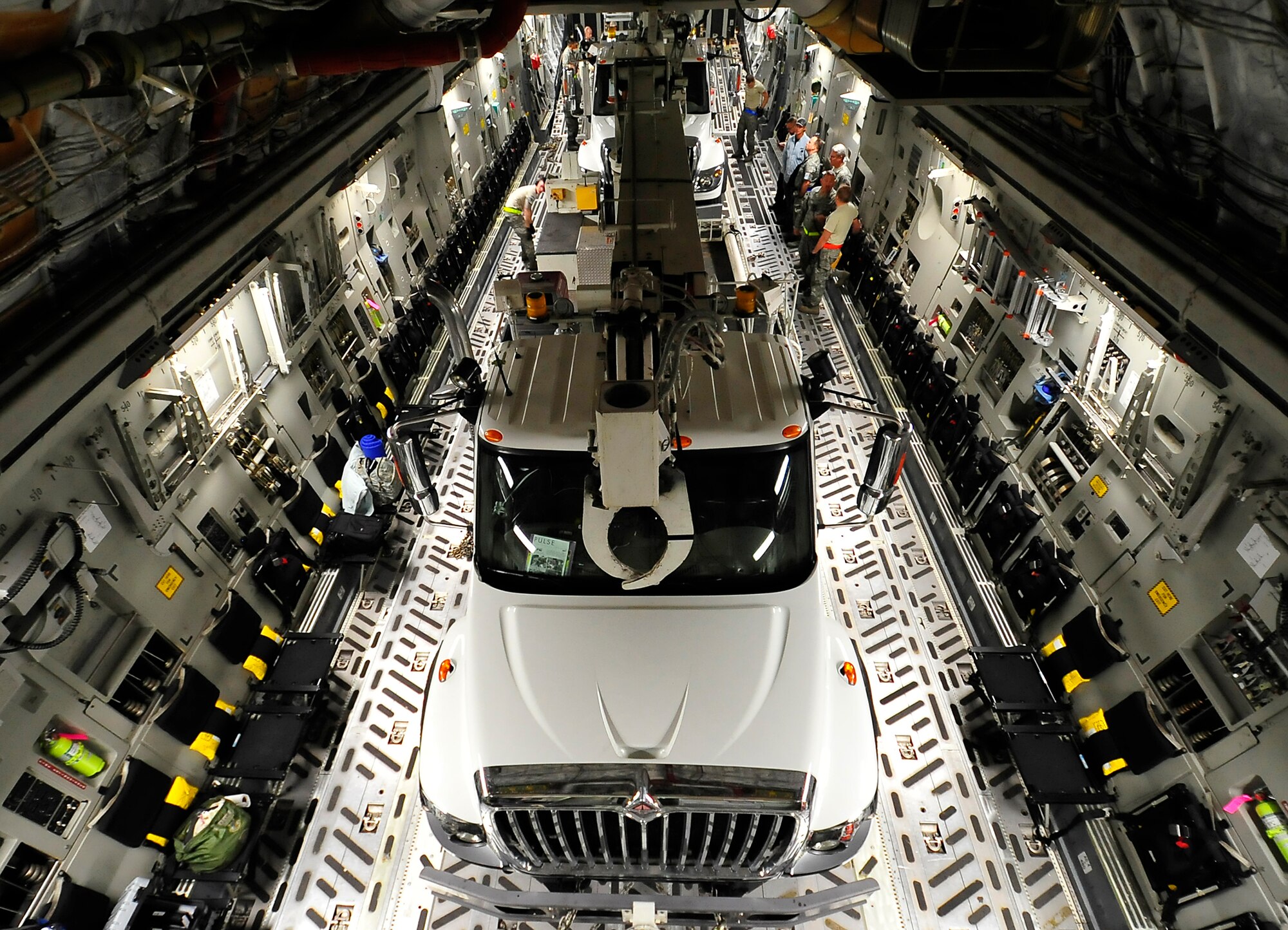 Two utility trucks are chained down to the cargo bay of a C-17 Globemaster III at Sky Harbor Air National Guard Base in Phoenix, Ariz., Nov. 3. Airmen of the 732nd Airlift Squadron picked-up the trucks and their drivers and delivered them to Stewart Air National Guard Base in Newburgh, N.Y., where they will be used to help repair downed powerlines throughout the region. (U.S. Air Force photo by Shawn J. Jones)