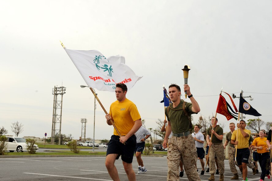 U.S. Navy Petty Officer 3rd Class Sam Klueber and U.S. Marine Corps Lance Cpl. Thomas Trujillo, both law enforcement personnel carry the torch and Special Olympics flag during the annual Special Olympics Torch Run on Kadena Air Base, Japan, Nov. 3, 2012. The run was to commemorate the 13th Annual Kadena Special Olympics Games that is scheduled for Nov. 17. (U.S. Air Force photo/Airman 1st Class Brooke P. Beers)
