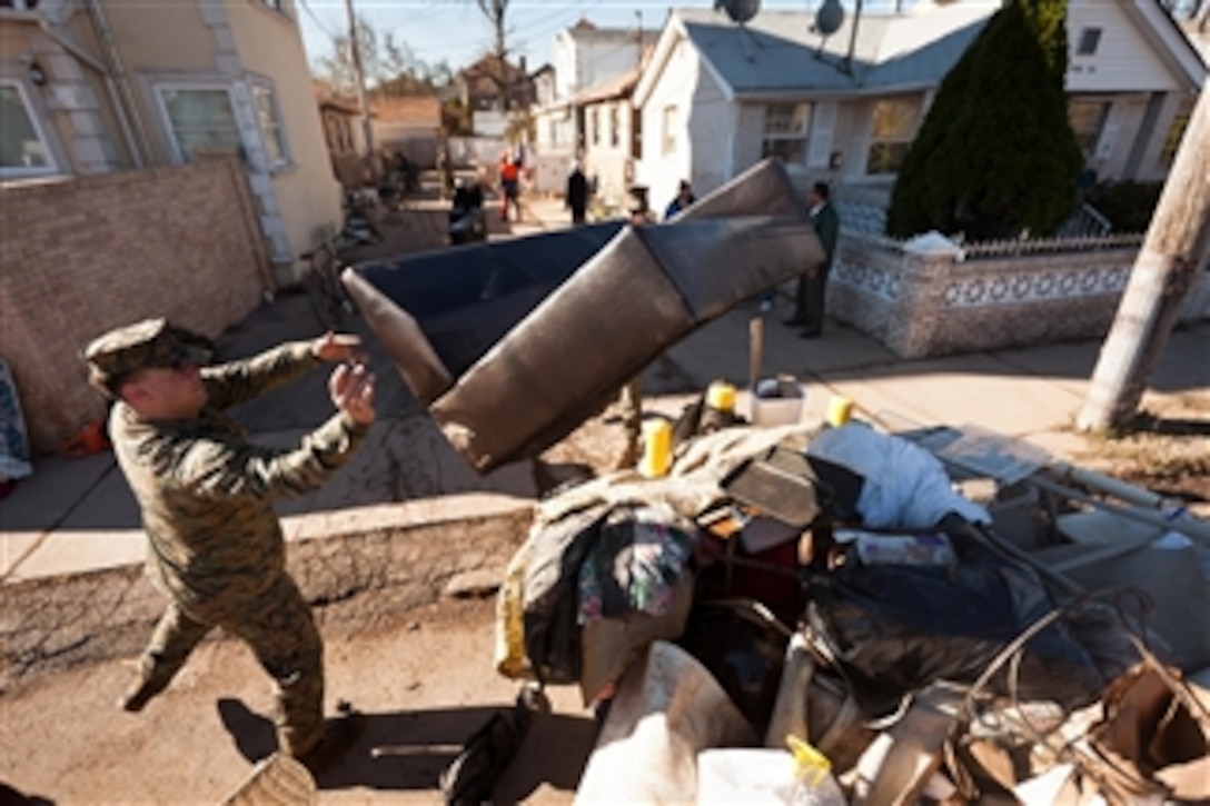 U.S. Marine Cpl. Thomas Cavallo, left, and Lance Cpl. Corey Shaw, obscured, throw a couch on a pile in the street in Staten Island, N.Y., on Nov. 4, 2012.  Marines and sailors with the 26th Marine Expeditionary Unit are working in the communities to support Hurricane Sandy disaster relief efforts in New York and New Jersey.  The expeditionary unit is able to provide generators, fuel, clean water, and helicopter lift capabilities to aid in the disaster relief efforts.  