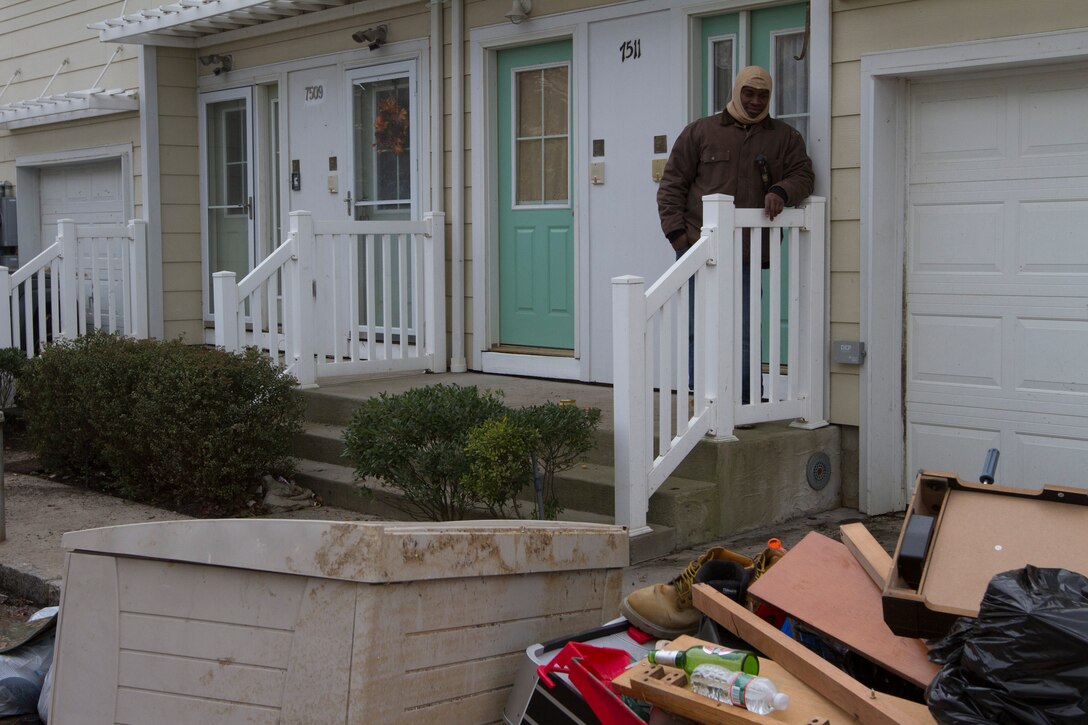 Sgt. Michael F. Blake, a motor transportation clerk with 1st Marine Corps District, looks at the heaps of ruined possessions piling on the streets of his neighborhood following the devastation left by Hurricane Sandy Nov. 1 in Far-Rockaway, N.Y.