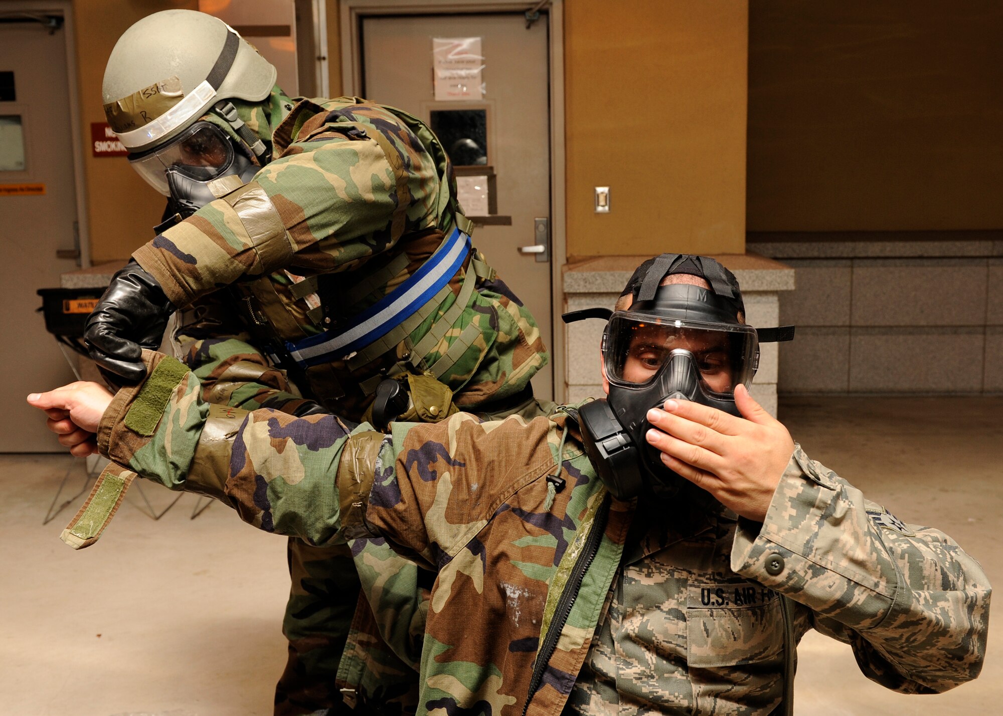 Staff Sgt. Robert Williams, left, helps Senior Airman Dennis Petzola, 8th Civil Engineer Squadron remove his contaminated Mission Oriented Protective Posture gear during exercise Beverly Bulldog 13-1 at Kunsan Air Base, Republic of Korea, Nov. 6, 2012. After finding contamination on his teammate, Williams called it in and proceeded to help him remove the gear. (U.S. Air Force photo/Senior Airman Marcus Morris)