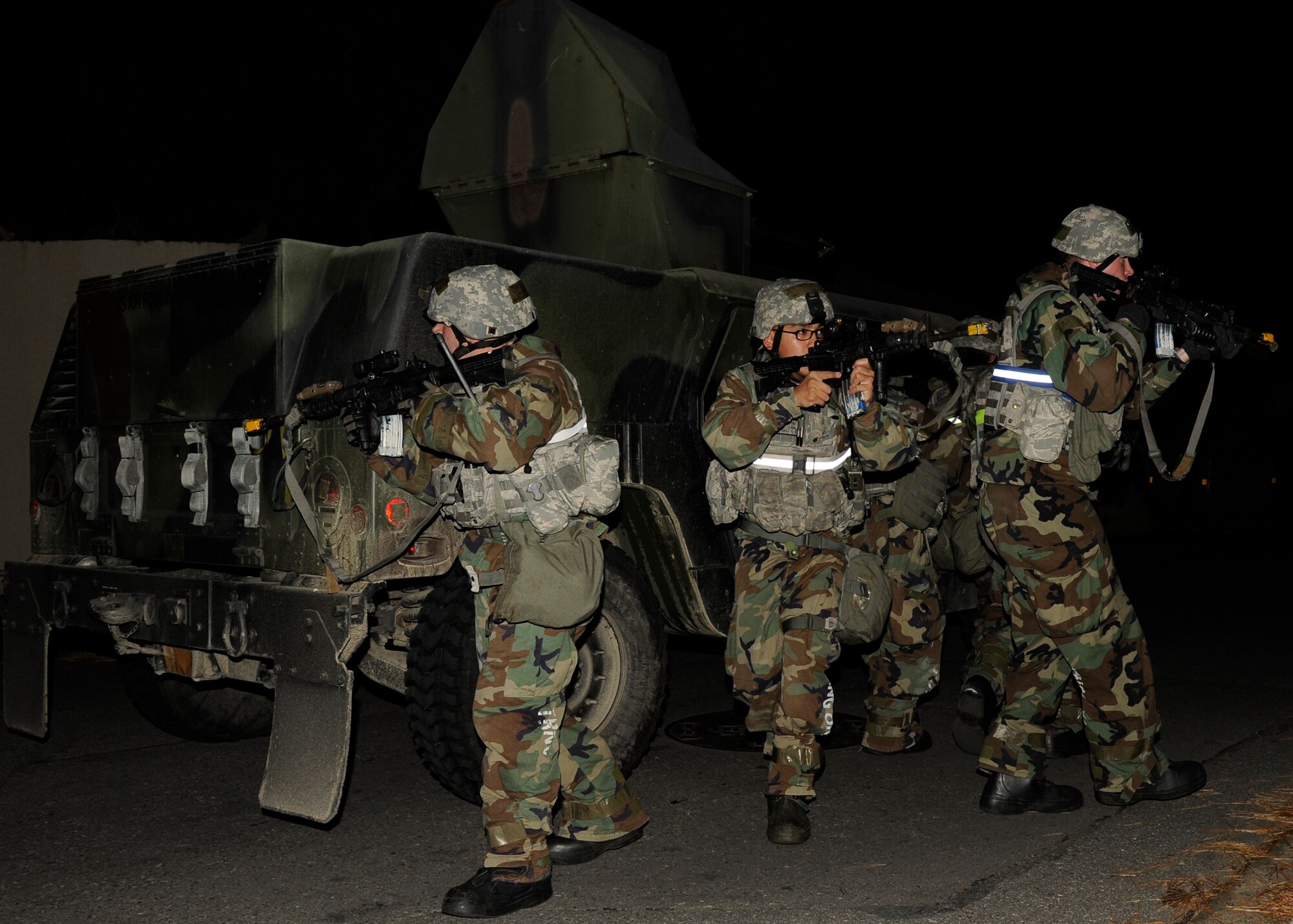 8th Security Forces Squadron  members from left, Airman 1st Class Edward Soutra, Staff Sgt. Travis Martho, and Senior Airman Christopher Bright, use a Humvee  for cover as they sweep the area for Opposing Forces role-players during exercise Beverly Bulldog 13-1 at Kunsan Air Base, Republic of Korea, Nov. 6, 2012. The Airmen joined with more security forces members to clear the 8th Communications Squadron compound of enemy presence. (U.S. Air Force photo/Senior Airman Marcus Morris)