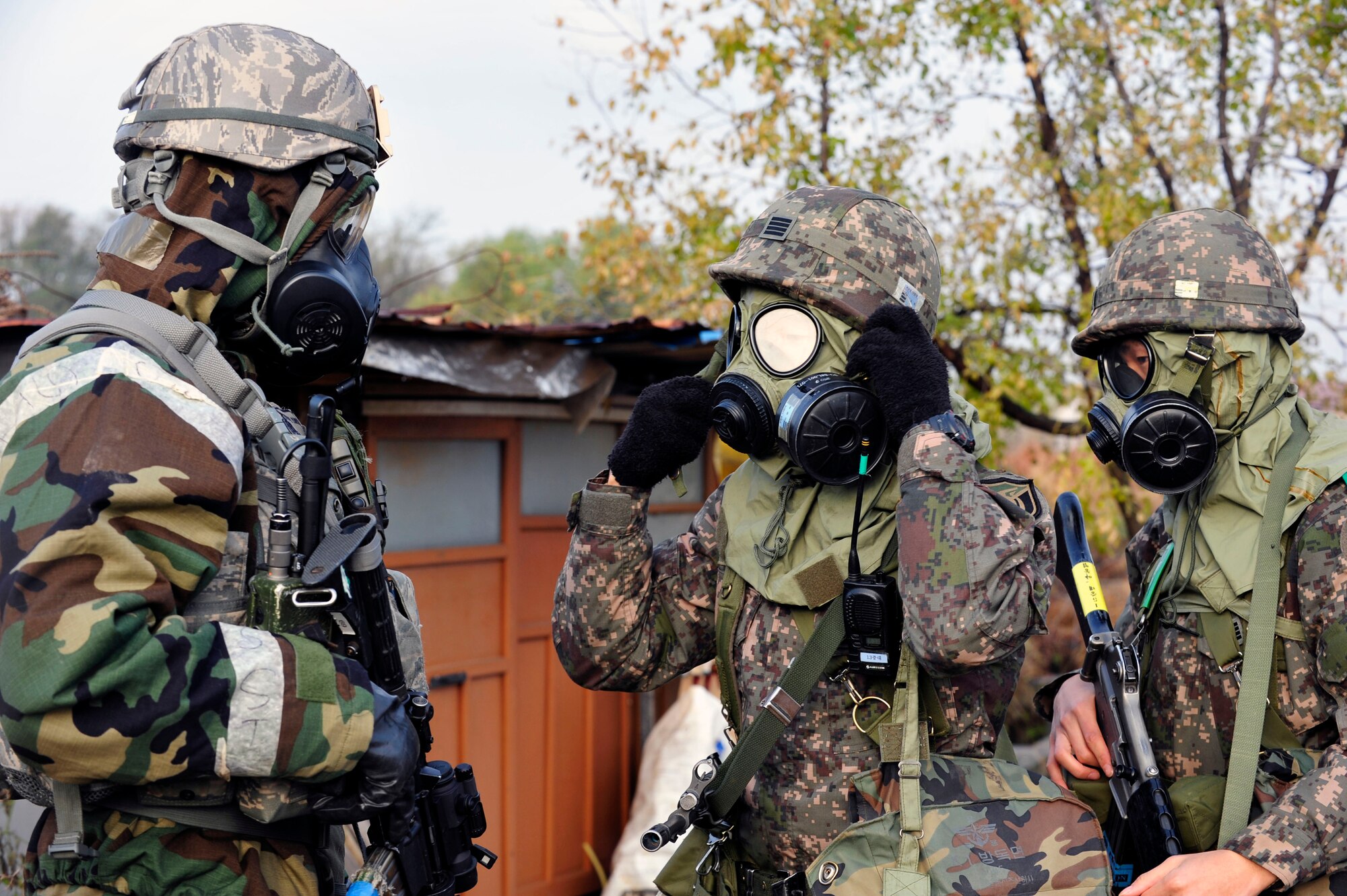 Tech. Sgt. Michael Yurco, 51st Security Forces Squadron flight chief, and two Republic of Korea Army 4th Battalion 51st Division soldiers perform buddy-checks to ensure the proper wear of Mission Oriented Protective Posture gear during operational readiness exercise Beverly Bulldog 13-01 at Osan Air Base, Republic of Korea, Nov. 6, 2012. The week-long exercise tests Osan Airmen’s abilities during a heightened state of readiness while providing combat ready forces for close air support, air strike control, counter air, interdiction, theater airlift, and communications in the defense of the Republic of Korea. (U.S. Air Force photo/Airman 1st Class Alexis Siekert)