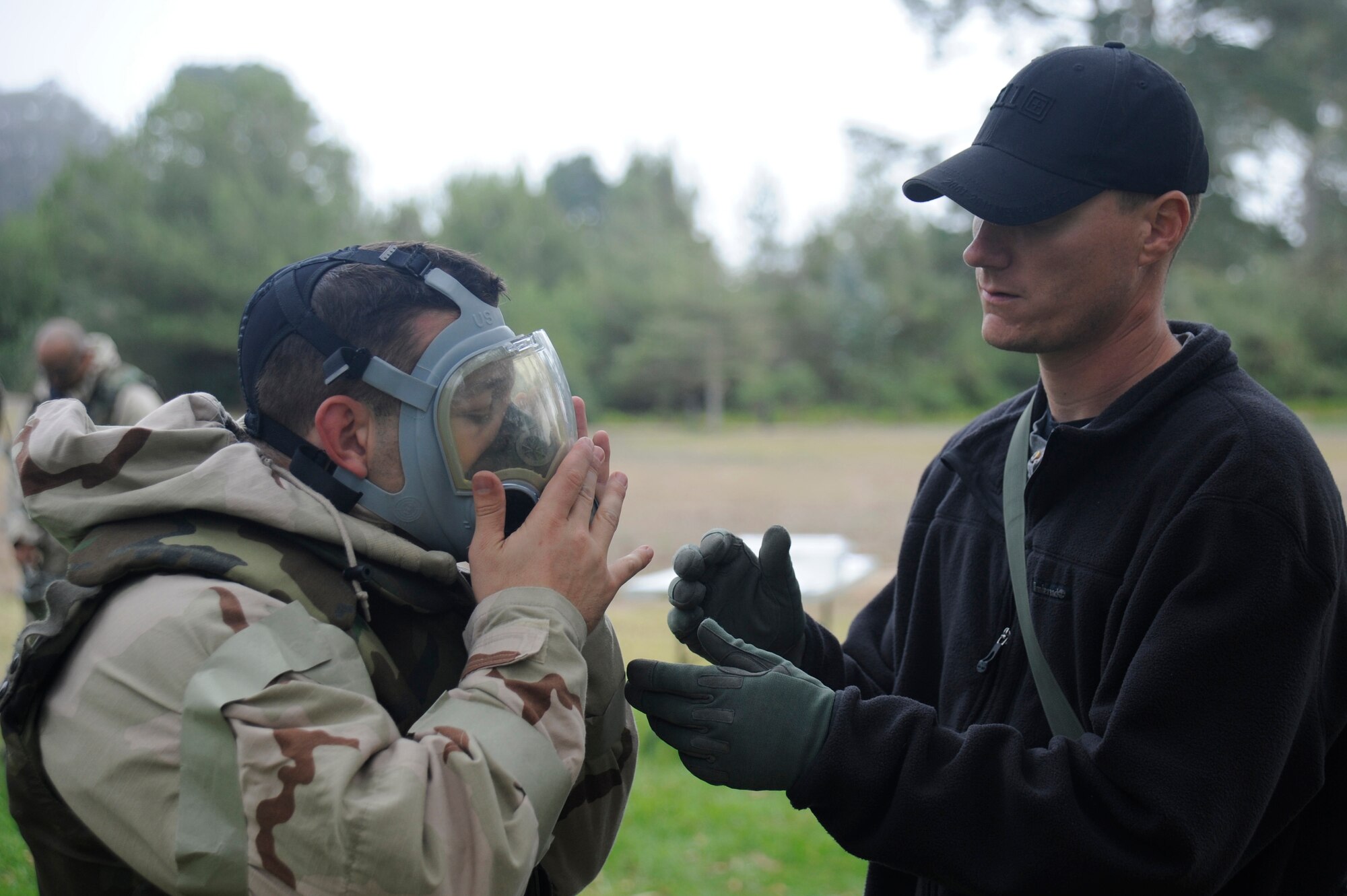 VANDENBERG AIR FORCE BASE, Calif. -- 
Nathan Lancor, 30th Civil Engineer Squadron emergency management trainer, helps Capt. Carman Leone, 30th Space Wing Staff Judge Advocate assistant, get a proper fit on his gas mask during deployment readiness training at Cocheo Park Thursday, Nov. 1, 2012. The use of CBRN protective gear is one of many essential skills on which Airmen are evaluated as they prepare for deployment. (U.S. Air Force photo/Michael Peterson)