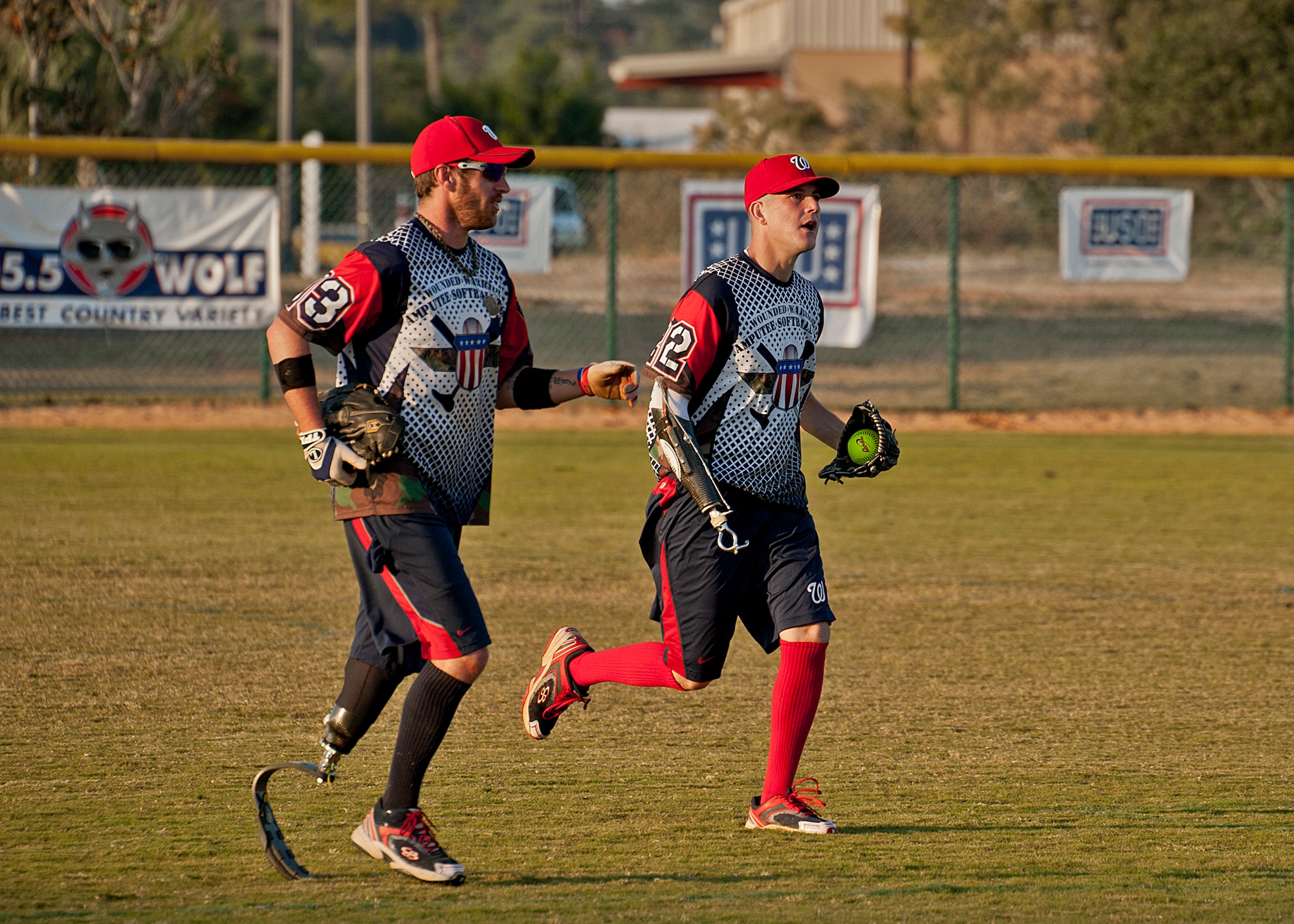 Nate Lindsey and Nick Clark, outfielders for the Wounded Warrior Amputee Softball Team, end the inning with a jog back to their dugout at the Morgan Sports Center in Destin, Fla., Nov. 3rd. Players from Eglin Air Force Base, Hurlburt Field and the Army 7th Special Forces Group, making up the Northwest Florida Armed Services Softball Team, played the WWAST in an effort to raise awareness of the sacrifices and resilience of military members. (U.S. Air Force photo/Randy Gon)