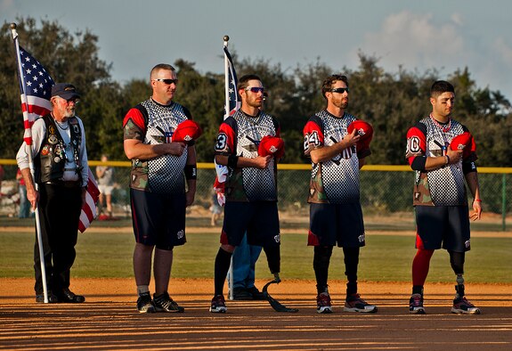 Players from the Wounded Warrior Amputee Softball Team, consisting of service members who have lost limbs in battle, joined with players from the Northwest Florida Armed Services Softball Team, in honoring America during the National Anthem at the Morgan Sports Center in Destin, Fla., Nov. 3rd. The two teams played to raise awareness of the sacrifices and resilience of military members. (U.S. Air Force photo/Randy Gon)
