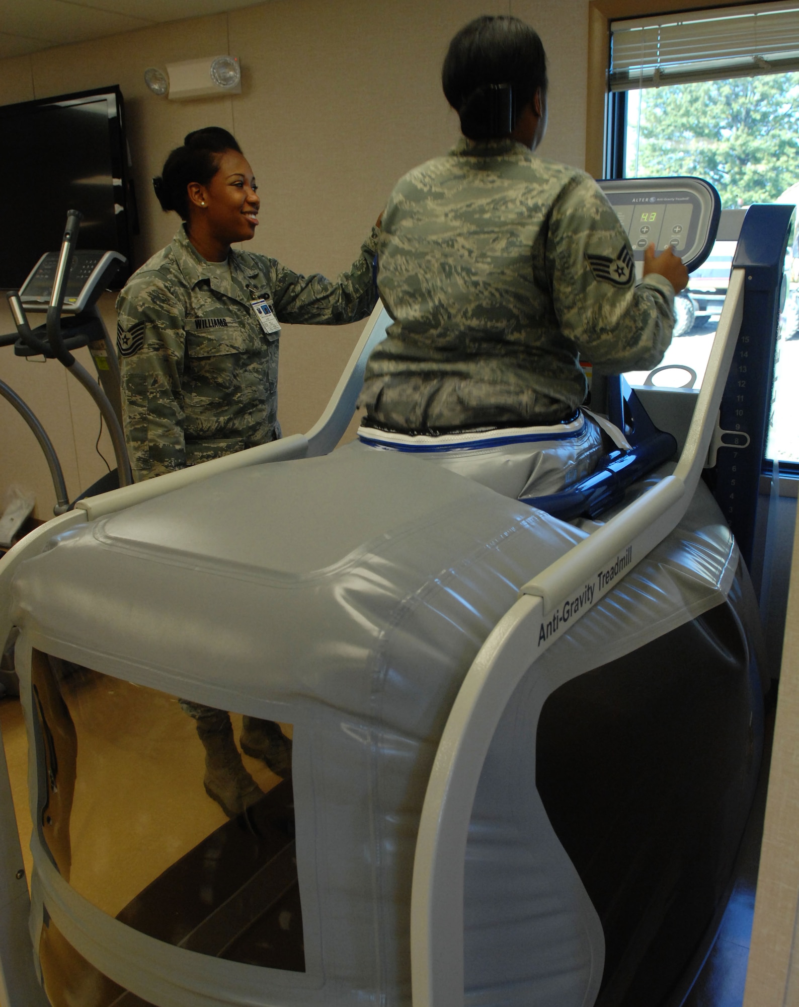 Tech. Sgt. Starr Williams, 633rd Medical Group physical therapy flight noncommissioned officer-in-charge, shows Staff Sgt. Iesha Ashley, 633rd Medical group physical therapy technician, the affects of the anti-gravity treadmill at Langley Air Force Base, Va., Oct. 25. Complex and bulky equipment like the treadmill can fit inside the new clinic, giving personnel more options when treating a patient. (U.S. Air Force Photo by Airman 1st Class Austin Harvill/Released) (Badge blurred for security reasons)