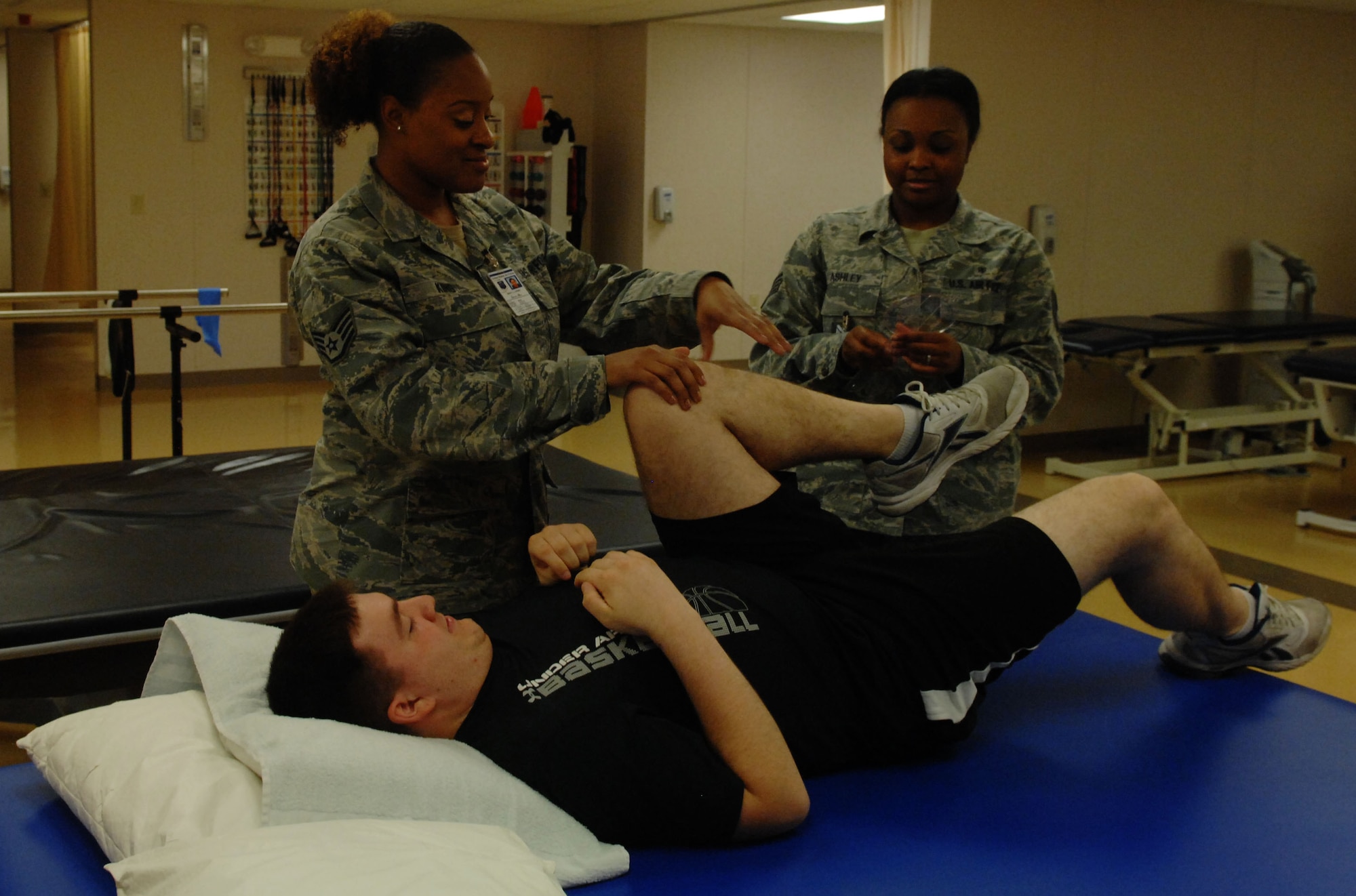 Staff Sgt. Iesha Ashley and Staff Sgt. Laneka King, both 633rd Medical group physical therapy technicians, measure the angle of a patient’s knee at Langley Air Force Base, Va., Oct. 25. The new, large beds at the clinic can accommodate patients who require measurements and other treatment. (U.S. Air Force Photo by Airman 1st Class Austin Harvill/Released) (Badge blurred for security reasons)