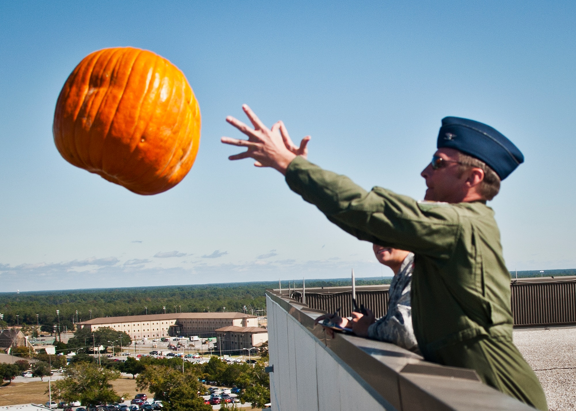 Col. David Hicks, the 53rd Wing commander, tosses a pumpkin off of Bldg. 350 toward a target on the ground during the 9th Annual Pumpkin Toss at Eglin Air Force Base, Fla., Nov. 6. Participants paid $5 for each toss.  Proceeds from the event, went to a Combined Federal Campign charity. (U.S. Air Force photo/Randy Gon)