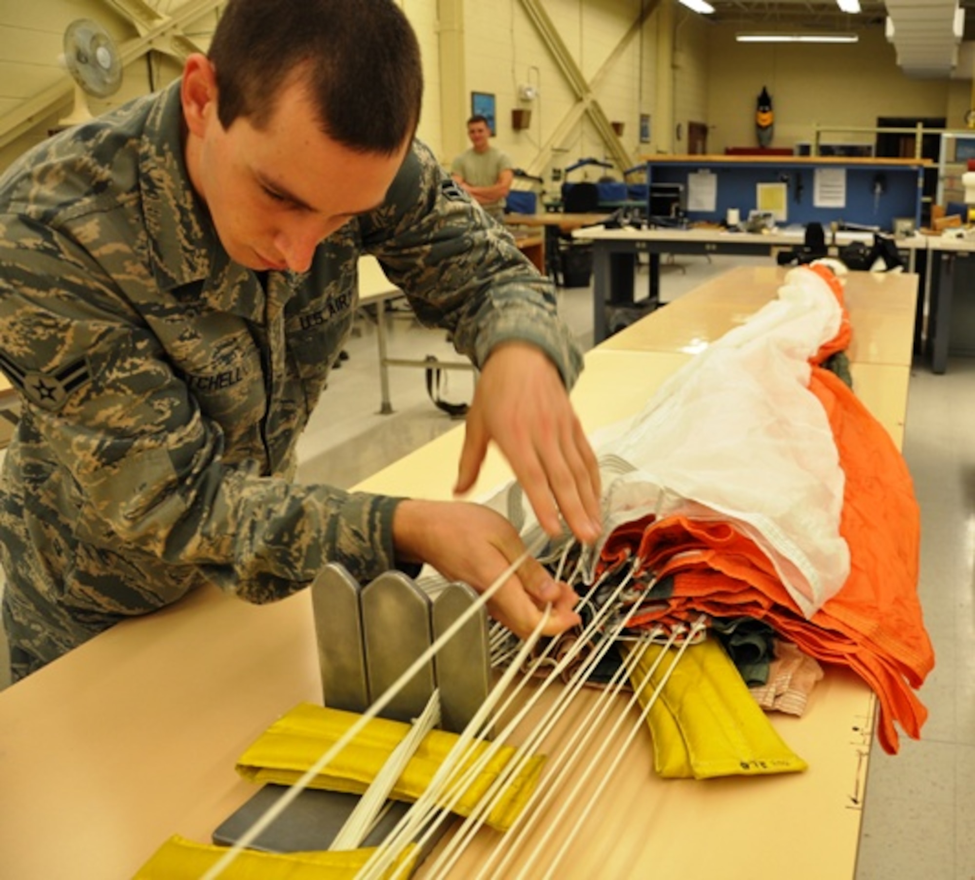 Airman 1st Class Tomas Mitchell, 325th Operations Support Squadron aircrew flight equipment specialist, separates each line of the parachute, checking for any weaknesses and ensuring there are no tangles or knots. (U.S. Air Force photo by Staff Sgt. Kirsten Wicker)  