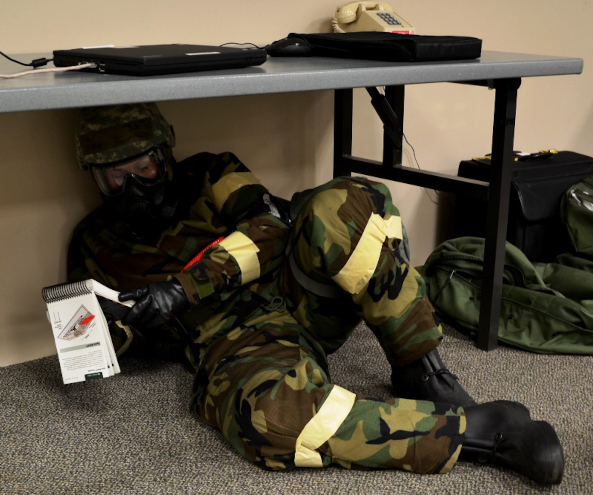 Tech. Sgt. Jennifer DeLucia, 446th Airlift Wing historian reviews her Airman’s Manual while taking cover from a simulated attack during an Operational Readiness Inspection scenario at Volk Field Combat Readiness Training Center, Wis. Oct. 18.  The 446th Airlift Wing teamed up with its active-duty brothers and sisters from the 62nd Airlift Wing and 627th Air Base Group for the inspection.  (Courtesy photo)