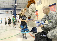 Senior Airman Addicus Niland, 902nd Security Forces Squadron patrolman, and McGruff the Crime Dog, hand out information packets to kindergartners at Randolph Elementary School Oct. 25 at Joint Base San Antonio-Randolph. McGruff is the mascot used by the National Crime Prevention Council to spread awareness of crime to children and Red Ribbon Week is an alcohol, tobacco, and other drug and violence prevention awareness campaign observed annually in October in the United States. (U.S. Air Force photo by Benjamin Faske)