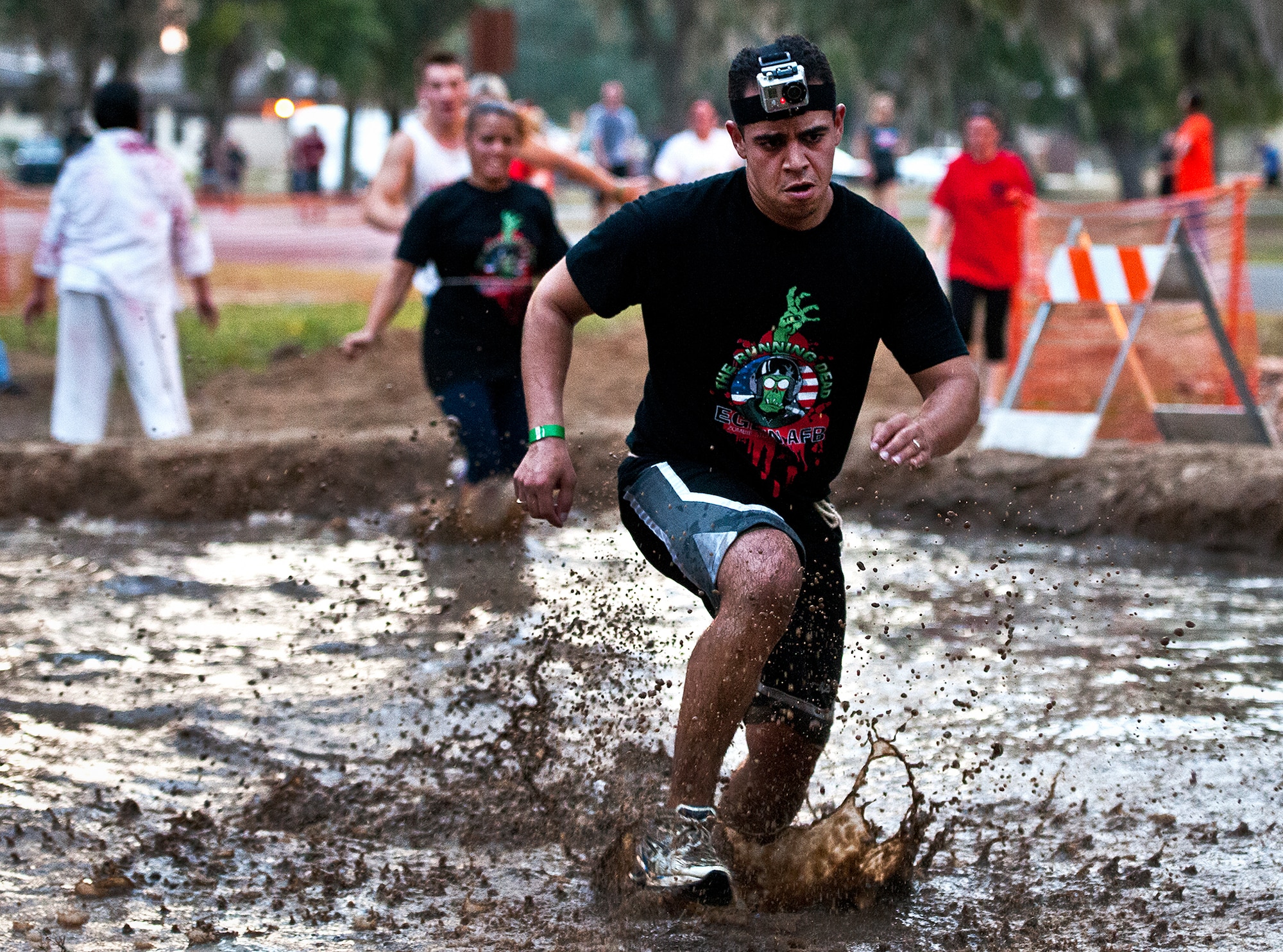 Runners jump in and run through a giant mud pit to escape the undead at the first-ever Zombie Stomp run at Eglin Air Force Base, Fla., Nov. 3.  More than 425 fearless runners braved zombie-infested woods, water and mud hazards and other obstacles over a 4.5 mile course.  (U.S. Air Force photo/Samuel King Jr.)