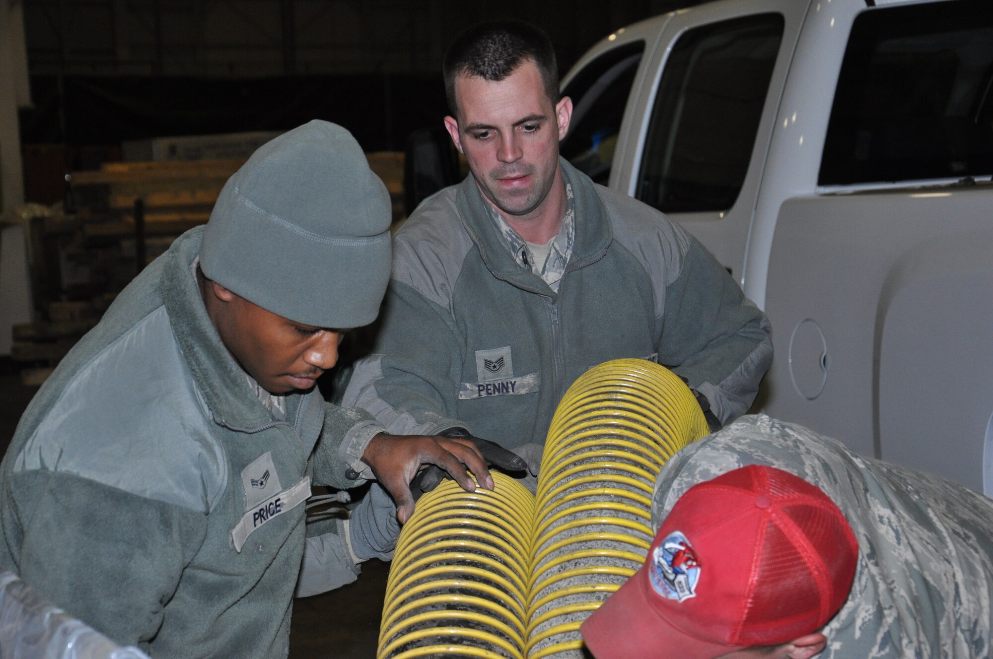 Staff Sgt. Richard Penny and Airman 1st Class Daquan Price, originally of the 633rd Civil Engineer Squadron from Joint Base Langley-Eustis, Va., help roll a large hose while staged at Joint Base McGuire-Dix-Lakehurst, N.J., Nov. 4, 2012, in preparation for hurricane relief operations. Approximately 50 Air Force civil engineers were sent from duty locations across the country to form the 331st Air Expeditionary Group, and were sent to pump flood water from critical areas effecting New York communities. (U.S. Air Force photo by Capt. Sybil Taunton/ Released)