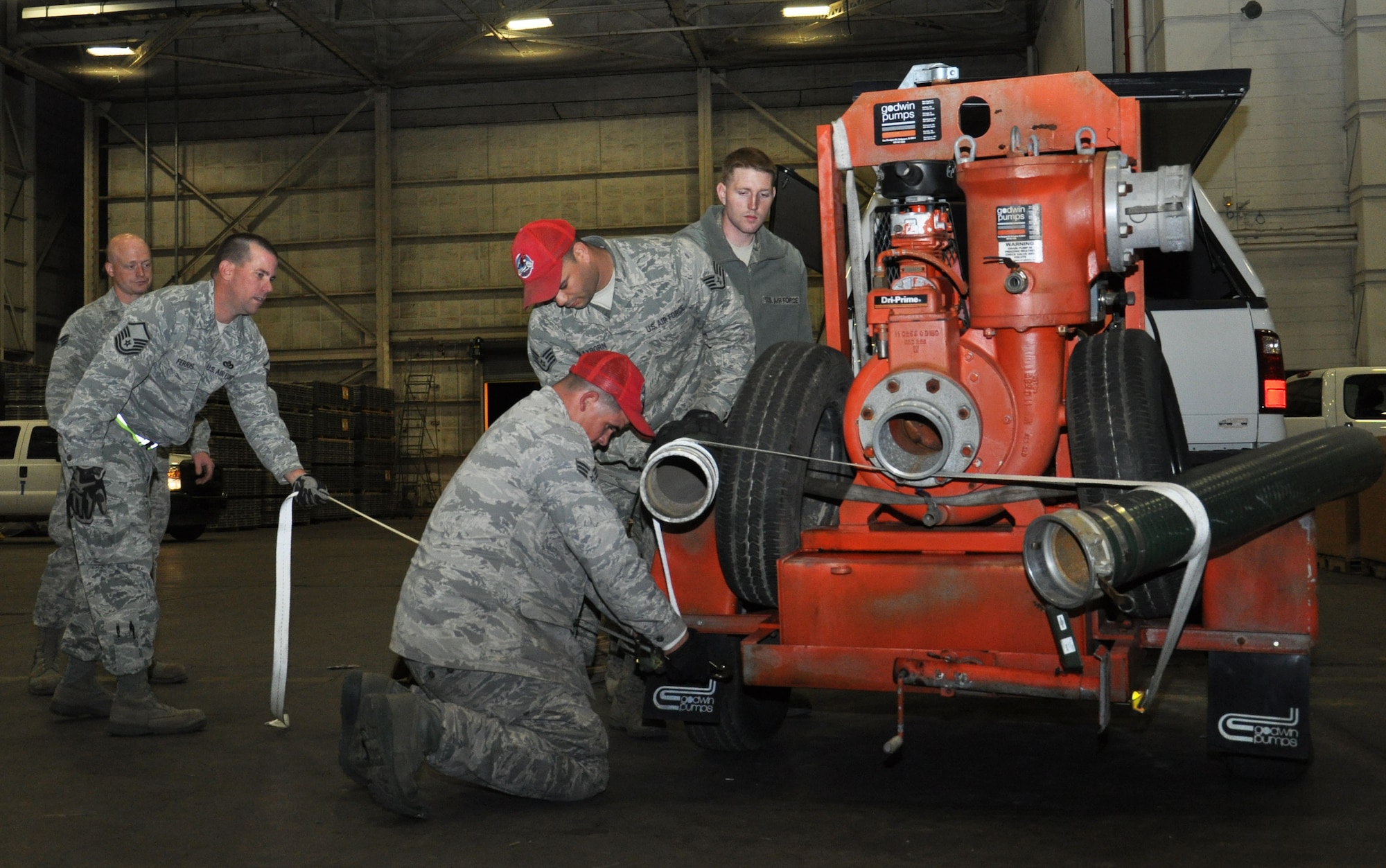 Members of the 331st Air Expeditionary Group strap down pump equipment while staged at Joint Base McGuire-Dix-Lakehurst, N.J., Nov. 4, 2012, and prepare for movement to Fort Hamilton, N.Y., in support of hurricane relief efforts. The 331st AEG is made up of nearly 50 Air Force civil engineers from various duty locations across the country, and 12 industrial pumps that will help clear flood water from critical areas damaged by Hurricane Sandy. (U.S. Air Force photo by Capt. Sybil Taunton/Released)