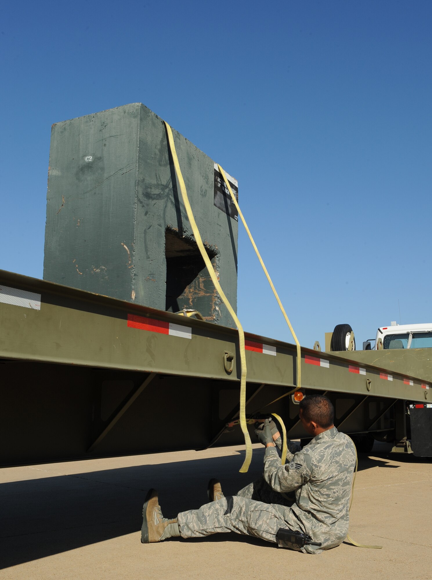 Senior Airman Pierre Brown, 2nd Logistics Readiness Squadron Vehicle Operations journeyman, ensures one side of a training block is tied down to a 45 foot trailer during a training scenario on Barksdale Air Force Base, La., Oct. 31. Vehicle operators support the Barksdale mission by driving aircrew to and from their aircraft as well as delivering parts to maintainers on the flightline. (U.S. Air Force photo/Airman 1st Class Benjamin Gonsier)(RELEASED)
