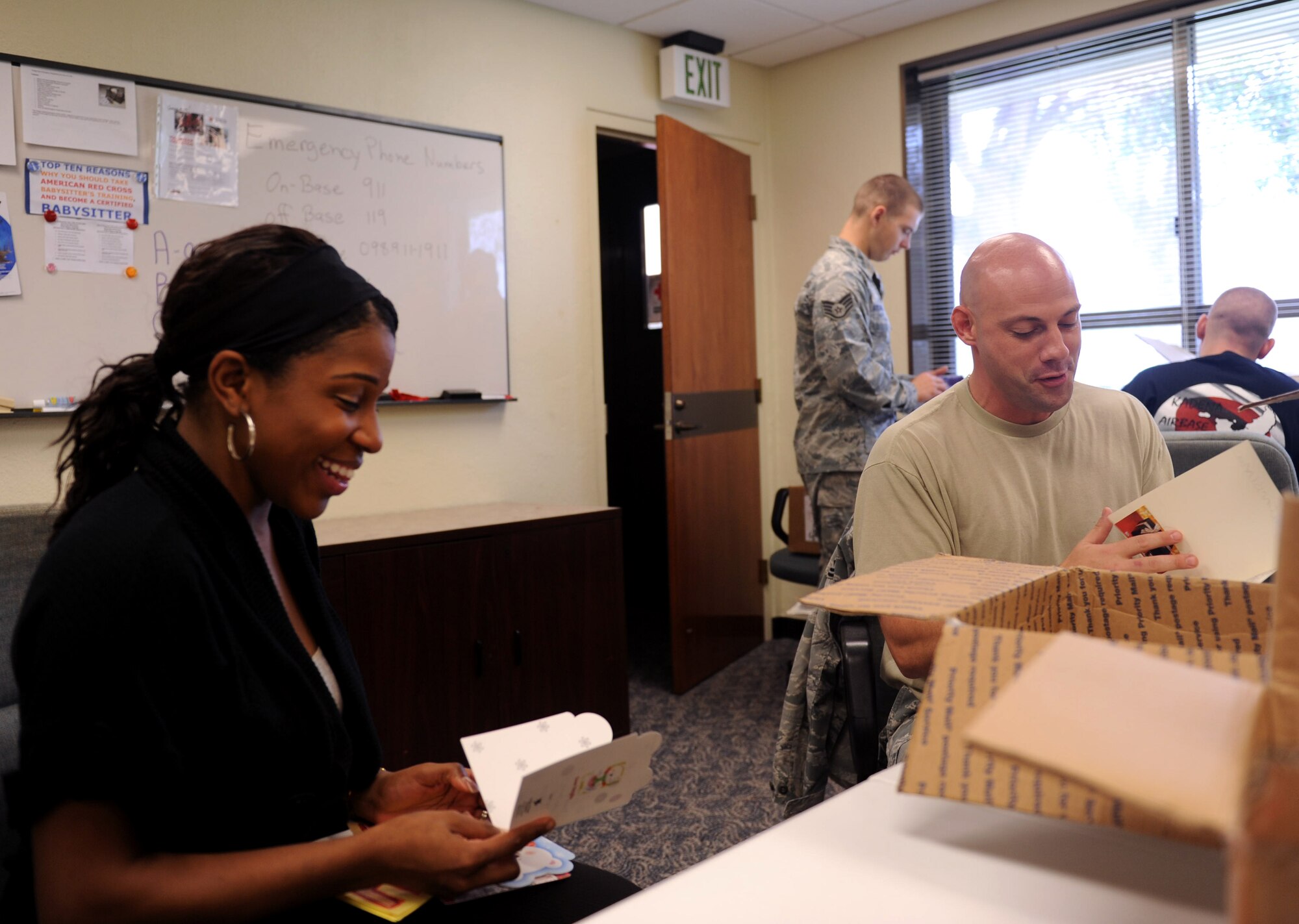 U.S. Air Force Staff Sgt. Janay Stokes, 18th Security Forces Squadron investigator, and Tech Sgt. Lee Dearnley, 18th Maintenance Operation Squadron loading standardization crew member, open Christmas cards during the American Red Cross Cards for Airmen screening on Kadena Air Base, Japan, Nov. 1, 2012. The American Red Cross will distribute Christmas cards to dining and lodging facilities, as well as other various locations during the upcoming holiday season. (U.S. Air Force photo/Airman 1st Class Hailey R. Davis)