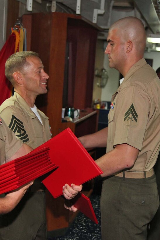 Corporal Daniel D. Burrell, motor transportation operator, 2nd Platoon, Battery B, Battalion Landing Team 3/5, 15th Marine Expeditionary Unit, shakes hands with 1st Sgt. Yomen J. English, 1st Sgt., Weapons Company, BLT 3/5, 15th MEU, during the graduation ceremony for a Corporals course aboard the USS Rushmore, Nov. 2. The Marines devoted 81 hours to physical training, lectures, practical application, performance evaluations, written evaluations and counselings during the course. The 15th MEU is deployed as part of the Peleliu Amphibious Ready Group as a theater reserve and crisis response.