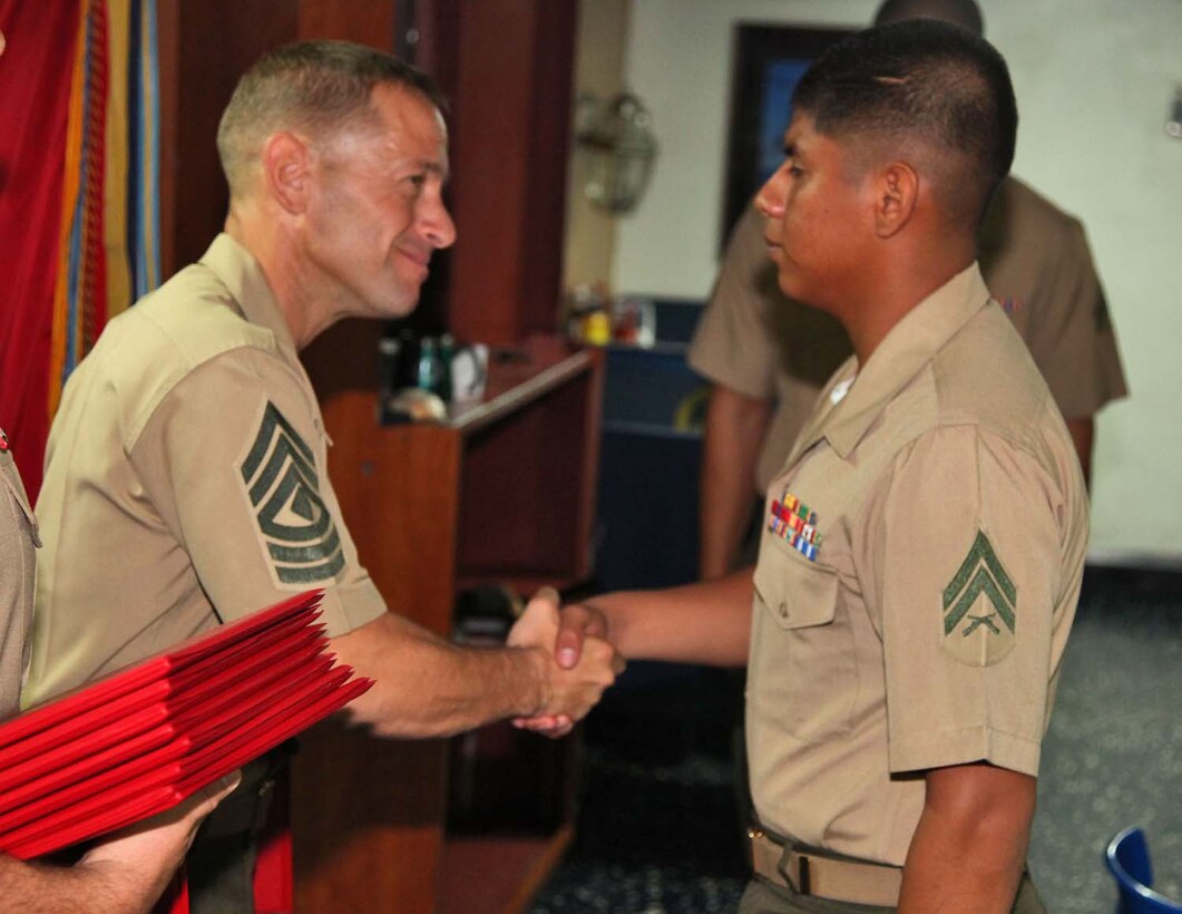 Corporal Edgar Carachure, artillery cannoneer, 1st Platoon, Battery B, Battalion Landing Team 3/5, 15th Marine Expeditionary Unit, shakes hands with 1st Sgt. Yomen J. English, 1st Sgt., Weapons Company, BLT 3/5, 15th MEU, during the graduation ceremony for a Corporals course aboard the USS Rushmore, Nov. 2. The Marines devoted 81 hours to physical training, lectures, practical application, performance evaluations, written evaluations and counselings during the course. The 15th MEU is deployed as part of the Peleliu Amphibious Ready Group as a theater reserve and crisis response.