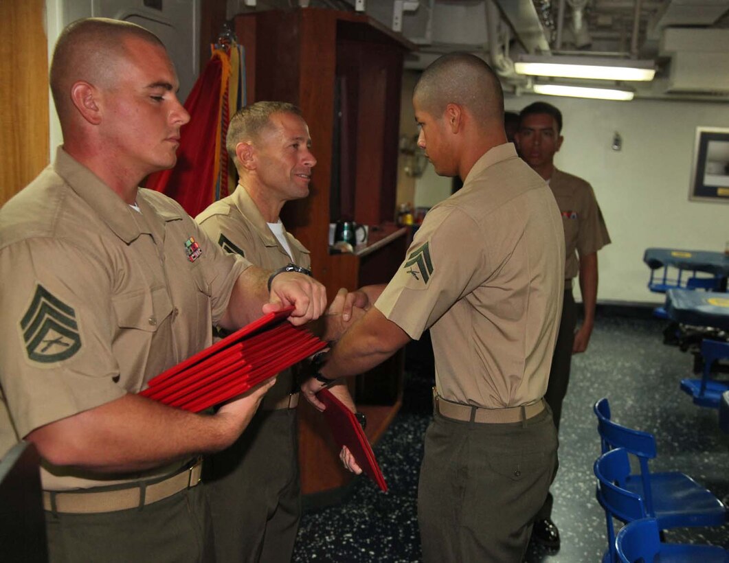 Corporal Andres Chavarin, field wireman, 2nd Platoon, Battery B, Battalion Landing Team 3/5, 15th Marine Expeditionary Unit, shakes hands with 1st Sgt. Yomen J. English, 1st Sgt., Weapons Company, BLT 3/5, 15th MEU, during the graduation ceremony for a Corporals course aboard the USS Rushmore, Nov. 2. The Marines devoted 81 hours to physical training, lectures, practical application, performance evaluations, written evaluations and counselings during the course. The 15th MEU is deployed as part of the Peleliu Amphibious Ready Group as a theater reserve and crisis response.