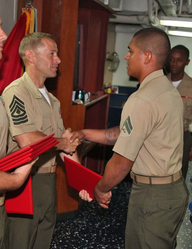 Corporal Jonathan K. Ebalaroza, fire direction controller, 1st Platoon, Battery B, Battalion Landing Team 3/5, 15th Marine Expeditionary Unit, shakes hands with 1st Sgt. Yomen J. English, 1st Sgt., Weapons Company, BLT 3/5, 15th MEU, during the graduation ceremony for a Corporals course aboard the USS Rushmore, Nov. 2. The Marines devoted 81 hours to physical training, lectures, practical application, performance evaluations, written evaluations and counselings during the course. The 15th MEU is deployed as part of the Peleliu Amphibious Ready Group as a theater reserve and crisis response.