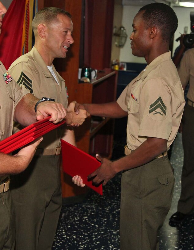 Corporal Pierre K. Justin, administration specialist, Command Element, 15th Marine Expeditionary Unit, shakes hands with 1st Sgt. Yomen J. English, 1st Sgt., Weapons Company, Battalion Landing Team 3/5, 15th MEU, during the graduation ceremony for a Corporals course aboard the USS Rushmore, Nov. 2. The Marines devoted 81 hours to physical training, lectures, practical application, performance evaluations, written evaluations and counselings during the course. The 15th MEU is deployed as part of the Peleliu Amphibious Ready Group as a theater reserve and crisis response.