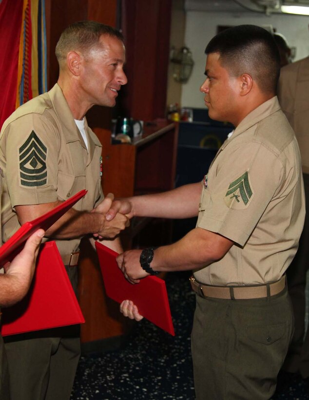 Corporal Miguel A. Lopez, supply clerk, Combat Logistics Battalion 15, 15th Marine Expeditionary Unit, shakes hands with 1st Sgt. Yomen J. English, 1st Sgt., Weapons Company, Battalion Landing Team 3/5, 15th MEU, during the graduation ceremony for a Corporals course aboard the USS Rushmore, Nov. 2. The Marines devoted 81 hours to physical training, lectures, practical application, performance evaluations, written evaluations and counselings during the course. The 15th MEU is deployed as part of the Peleliu Amphibious Ready Group as a theater reserve and crisis response.