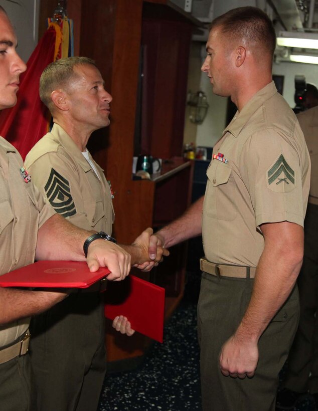 Corporal Joshua Plachy, military policeman, Military Police Detachment, Combat Logistics Battalion 15, 15th Marine Expeditionary Unit, shakes hands with 1st Sgt. Yomen J. English, 1st Sgt., Weapons Company, Battalion Landing Team 3/5, 15th MEU, during the graduation ceremony for a Corporals course aboard the USS Rushmore, Nov. 2. The Marines devoted 81 hours to physical training, lectures, practical application, performance evaluations, written evaluations and counselings during the course. The 15th MEU is deployed as part of the Peleliu Amphibious Ready Group as a theater reserve and crisis response.