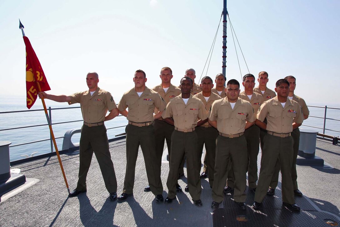 Recent graduates of Corporals course stand at parade rest on the forecastle of the USS Rushmore, Nov. 2. The Marines devoted 81 hours to physical training, lectures, practical application, performance evaluations, written evaluations and counselings during the course. The 15th MEU is deployed as part of the Peleliu Amphibious Ready Group as a theater reserve and crisis response.