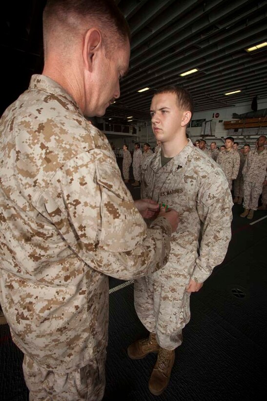 Corporal Kyle Bond, cyber network operator, Command Element, 15th Marine Expeditionary Unit, receives a Navy and Marine Corps Achievement Medal for his performance during pre-deployment training in a ceremony in the hanger bay of the USS Peleliu Nov. 1.  The first-of-the-month formation highlighted those Marines who received awards or were promoted.  The 15th MEU is deployed as part of the Peleliu Amphibious Ready Group as a theater reserve and crisis response force throughout U.S. Central Command and the U.S. 5th Fleet area of responsibility.