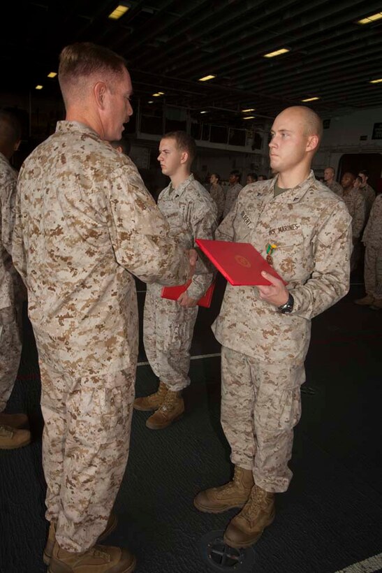 Lance Cpl. Matthew Gilbert, intelligence analyst, Command Element, 15th Marine Expeditionary Unit, receives Navy and Marine Corps Achievement Medal for his performance during pre-deployment training in a ceremony in the hanger bay of the USS Peleliu Nov. 1.  The first-of-the-month formation highlighted those Marines who received awards or were promoted.  The 15th MEU is deployed as part of the Peleliu Amphibious Ready Group as a theater reserve and crisis response force throughout U.S. Central Command and the U.S. 5th Fleet area of responsibility.