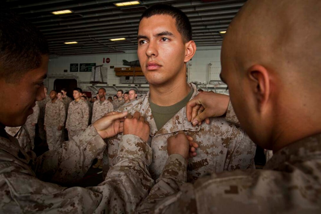 Newly promoted Cpl. Brendon Burke-Adams, cyber network operator, Command Element, 15th Marine Expeditionary Unit, receives his new chevrons during a ceremony in the hangar bay of the USS Peleliu Nov. 1.   The first-of-the-month formation highlighted those Marines who received awards or were promoted.  The 15th MEU is deployed as part of the Peleliu Amphibious Ready Group as a theater reserve and crisis response force throughout U.S. Central Command and the U.S. 5th Fleet area of responsibility.
