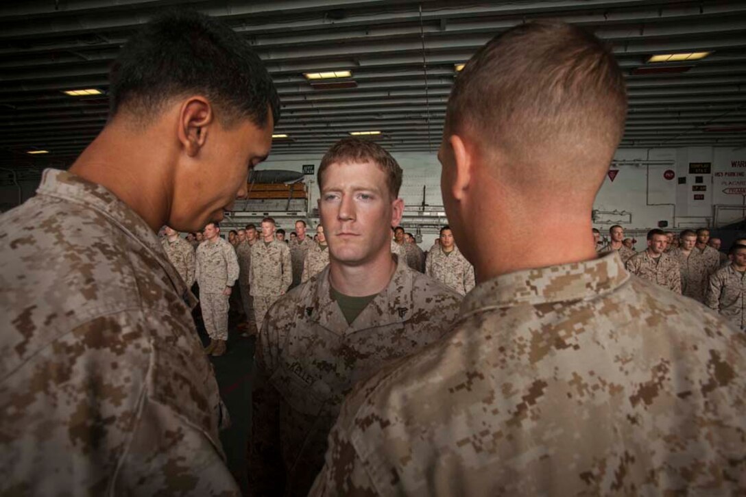 Newly promoted Cpl. Edward Kelly, Security Platoon, Command Element, 15th Marine Expeditionary Unit, receives his new chevrons during a ceremony in the hangar bay of the USS Peleliu Nov. 1.   The first-of-the-month formation highlighted those Marines who received awards or were promoted.  The 15th MEU is deployed as part of the Peleliu Amphibious Ready Group as a theater reserve and crisis response force throughout U.S. Central Command and the U.S. 5th Fleet area of responsibility.