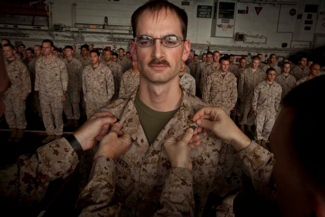 Newly promoted Cpl. William Privett, topographic analyst, Command Element, 15th Marine Expeditionary Unit, receives his new chevrons during a ceremony in the hangar bay of the USS Peleliu Nov. 1.   The first-of-the-month formation highlighted those Marines who received awards or were promoted.  The 15th MEU is deployed as part of the Peleliu Amphibious Ready Group as a theater reserve and crisis response force throughout U.S. Central Command and the U.S. 5th Fleet area of responsibility.