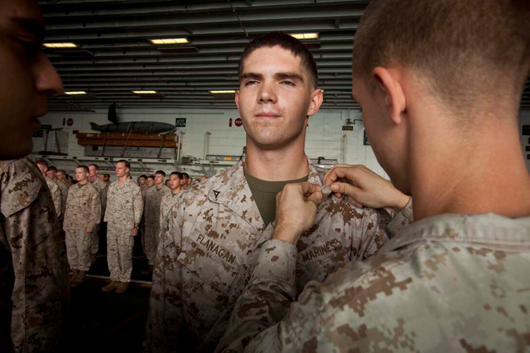 Newly promoted Lance Cpl. Brian Flanagan, field radio operator, Command Element, 15th Marine Expeditionary Unit, receives his new chevrons during a ceremony in the hangar bay of the USS Peleliu Nov. 1.   The first-of-the-month formation highlighted those Marines who received awards or were promoted.  The 15th MEU is deployed as part of the Peleliu Amphibious Ready Group as a theater reserve and crisis response force throughout U.S. Central Command and the U.S. 5th Fleet area of responsibility.