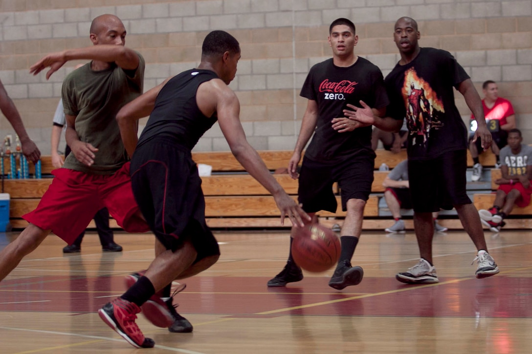 Lance Cpl. Dwight Dugar, an administrative specialist with Marine Corps Base Camp Pendleton, dribbles past Cpl. Jordan Dent, a radio operator with 9th Communication Battalion, during a basketball tournament at Paige Field house Oct. 31.
