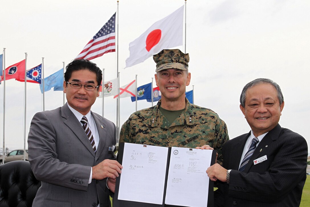 Ginowan City Mayor Atsushi Sakima, left, Maj. Gen. Peter J. Talleri, center, and Chatan Town Mayor Masaharu Noguni pose with the newly-signed Local Implementation Agreement in front of building 1 at Camp Foster Nov. 5. The agreement allows local residents access to evacuation routes through Marine Corps Air Station Futenma and Camp Foster in the event of a natural disaster, displaying the Marine Corps’ continued dedication to working together with the Okinawa community to ensure safety of its citizens. Talleri is the commanding general of Marine Corps Installations Pacific and Marine Corps Base Camp Butler. 