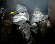Staff Sgt. Tim Vanden Haak, left, and Yi Son U, 8th Civil Engineer Squadron firefighters enter a burning building during exercise Beverly Bulldog 13-1 on Kunsan Air Base, Republic of Korea, Nov. 7, 2012. The firefighters used flashlights for illumination since the mortar attack took out the buildings power. (U.S. Air Force photo/Senior Airman Marcus Morris)