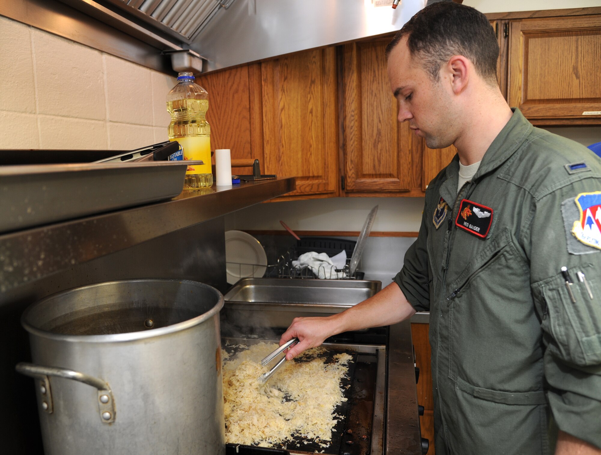 First Lt. Reid Gaiser, an instructor pilot with the 33rd Flying Training Squadron, grills onions for a dish during the October Singles’ International Gourmet Meal Opportunity held Oct. 29 in the Community Chapel Activity Center at Vance Air Force Base, Okla. SIGMO is a free meal prepared by a different unit each month for the single Airmen and families of deployed Airmen at Vance AFB. (U.S. Air Force photo/ Airman 1st Class Frank Casciotta)