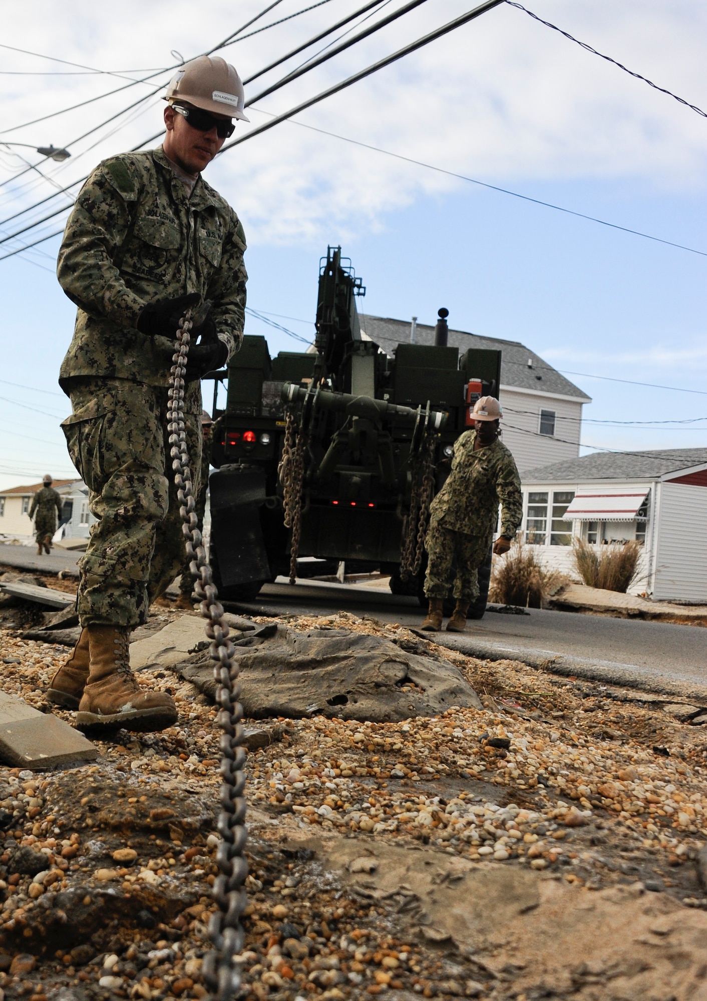 JOINT BASE MCGUIRE-DIX-LAKEHURST, N.J. — Seaman Collyn Schlagenhauff, Naval Mobile Construction Battalion 11 construction mechanic, attaches a heavy-wrecker truck chain to a derelict car Nov. 6, 2012, at Seaside Heights, N.J. Hurricane Sandy’s rage sent cars, boats and other things flying into houses and buildings all over the island. Schlagenhauff hails from Omaha, Neb. (U.S. Air Force photo by Airman 1st Class Ryan Throneberry/Released)