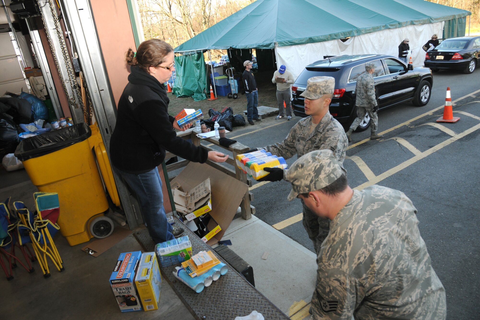 LINFORD, N.J. -- U.S. Air Force Airman 1st Class Richard Shia, left, gives a stack of tape to a volunteer at the Thompson Park Community Center in Monmouth County, N.J., Nov. 6. Shia, a native of Japan and member of the 305th Maintenance Group at Joint Base McGuire-Dix-Lakehurst, N.J., joined members of the base honor guard to help offload several thousand items to aid county residents impacted by Hurricane Sandy. (U.S. Air Force photo by Tech. Sgt. Zachary Wilson/Released)