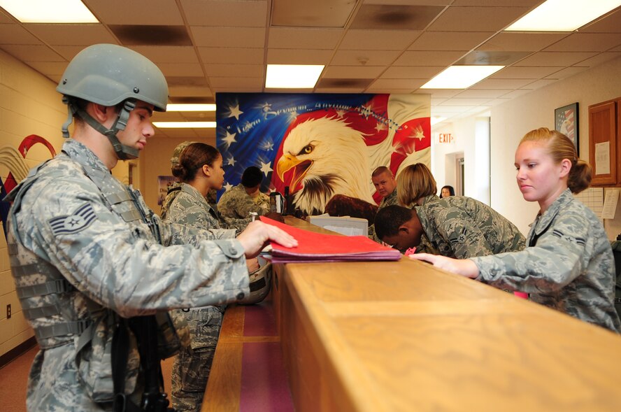 U.S. Air Force Staff Sgt. Matthew Halligan, 4th Security Forces Squadron military working dog handler, retrieves his deployment folder from Airman 1st Class Kymberlee Sequeira, 4th Force Support Squadron personnel apprentice, during Operational Readiness Exercise Coronet Warrior 12-05 on Seymour Johnson Air Force Base, N.C., Nov. 5, 2012. Personnel apprentices must ensure deploying Airmen have all training records, dog tags and personnel records on hand prior to their departure. (U.S. Air Force photo/Airman 1st Class Aubrey White/Released)