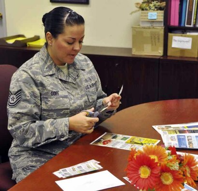 Tech. Sgt. Crystal Goff, March Airman & Family Readiness representative, clips donated coupons for shipment to the Kaiserslautern Army Community Services, located in Germany, where they will be readied for use by military family members. The coupon program is an outreach activity at March ARB, designed to help defray the costs incurred by military families while living abroad. On average, March sends 300 to 500 commissary and  AAFES-friendly coupons per week to the KACS. (U.S. Air Force photo by Darnell Gardner)