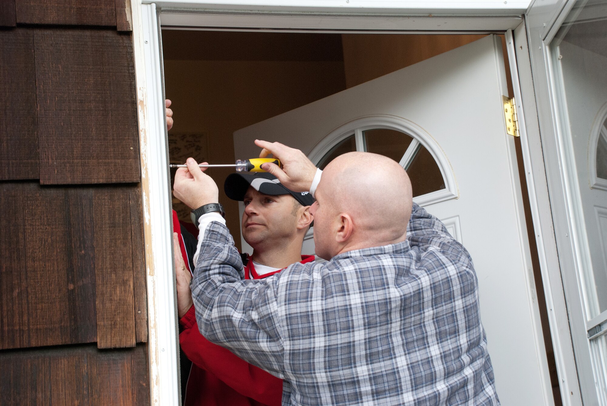Senior Master Sgt. Jamie Auger and Tech. Sgt. Matt Ladowitz, both of Air Mobility Command headquarters, work on the front door of a home Saturday in Belleville, Ill. The Scott Airmen were volunteering with Rebuilding Together Southwest Illinois.
