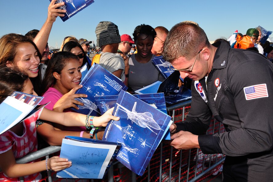 Staff Sgt. Brandon Rhodes, Thunderbirds tactical aircraft maintenance, signs autographs during the Wings Over Homestead air show at Homestead Air Reserve Base, Fla., Nov. 3. (U.S. Air Force photo/Tech. Sgt. Robert Gibson)