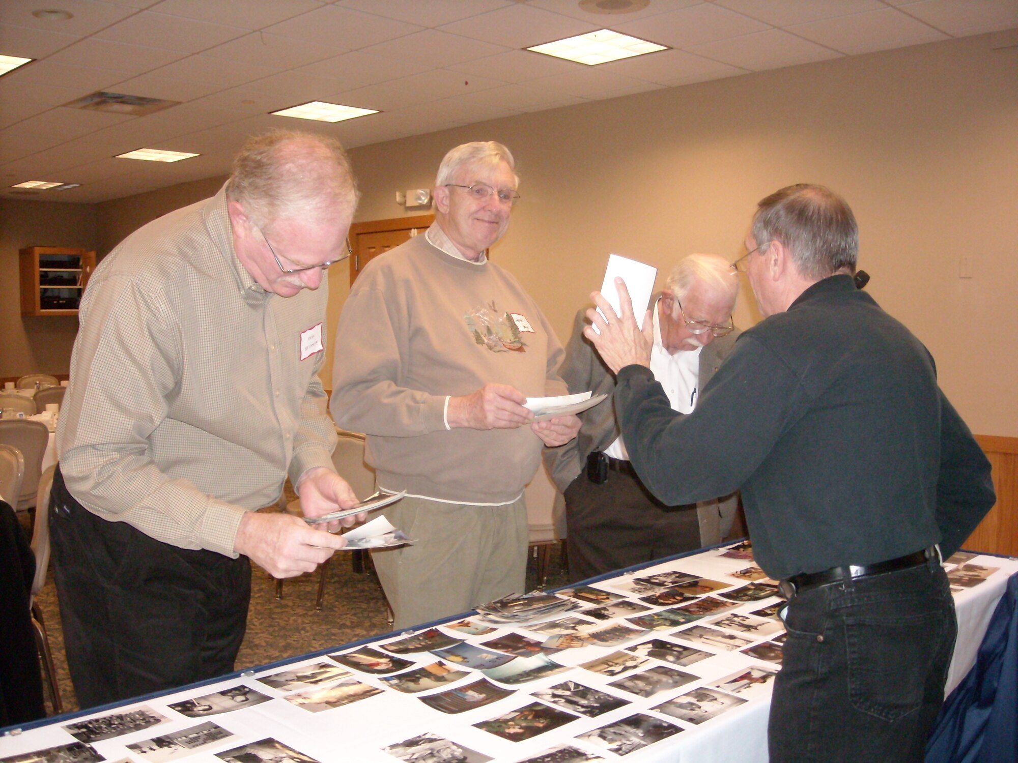 From left, Bob Hudson, former C-130E pilot, Howard Young, former C-130A flight engineer, Charles Van Guilder, former C-119 loadmaster and Tom Foss, former chief loadmaster, browse through historical photos at the 96th Associate Squadron reunion Oct. 20. (Courtesy Photo)