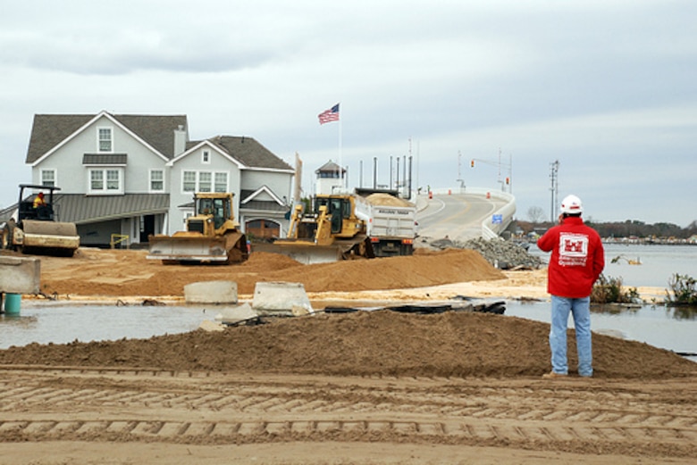 A Corps employee inspects the breach at Mantoloking, NJ as a result of Hurricane Sandy. The island has been cut off since a breach flooded the area at the end of the bridge. The engineers went to Mantoloking  to assess the damage and develop a plan to close the breach and reopen the bridge
