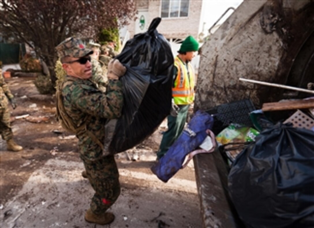 A Marine hoists a bag of trash into the back of a garbage truck in Staten Island, N.Y., on Nov. 5, 2012.  Marines and sailors with the 26th Marine Expeditionary Unit are working in the communities to support Hurricane Sandy disaster relief efforts in New York and New Jersey.  The expeditionary unit is able to provide generators, fuel, clean water, and helicopter lift capabilities to aid in the disaster relief efforts.  